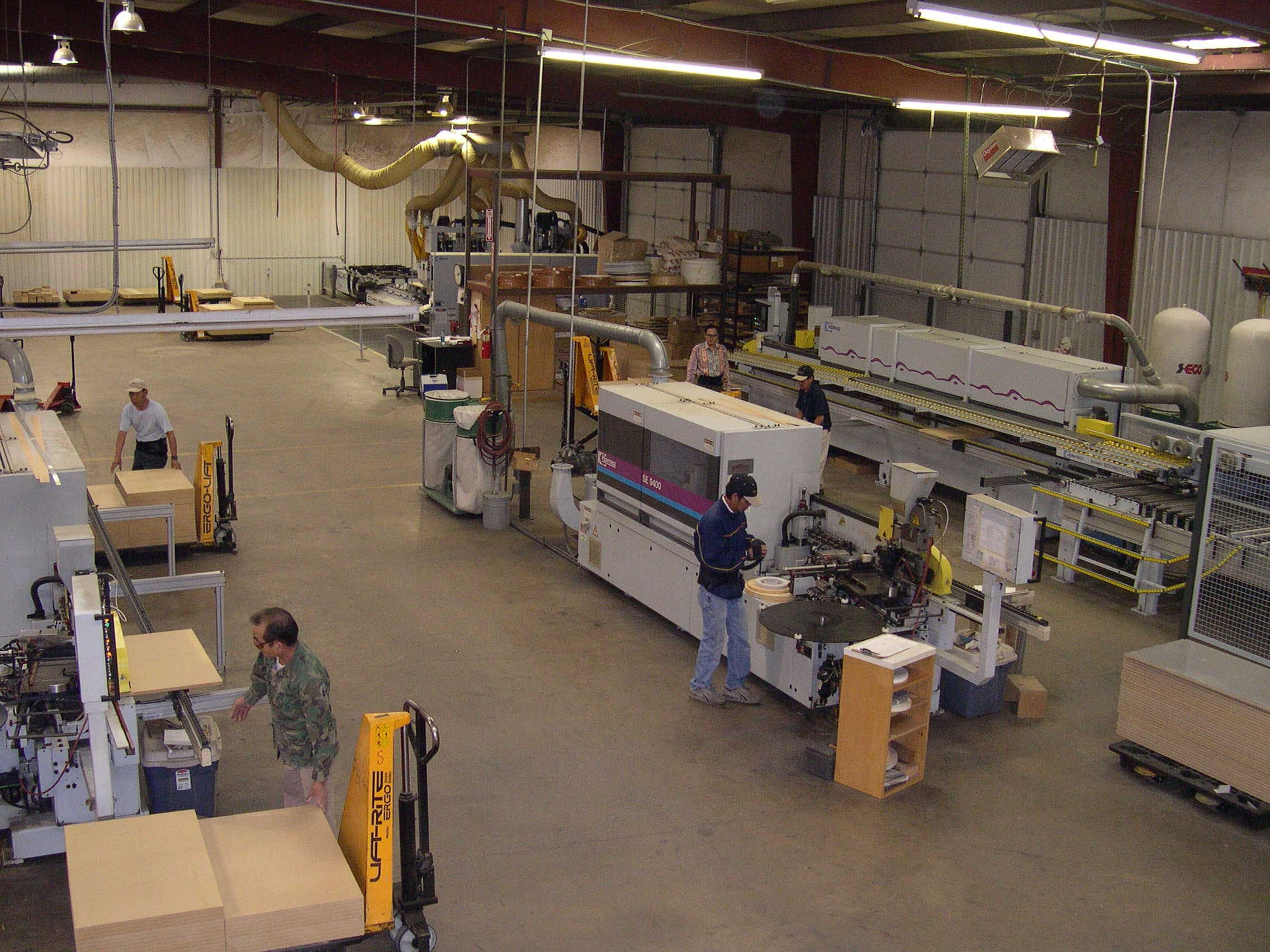 A HOMAG industrial machine processing wood panels, surrounded by wire safety fencing, in a clean warehouse.
