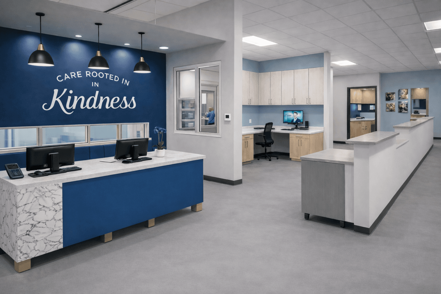Healthcare reception with a white and blue desk, pendant lighting, and a wall message about care, with office workstations beyond.
